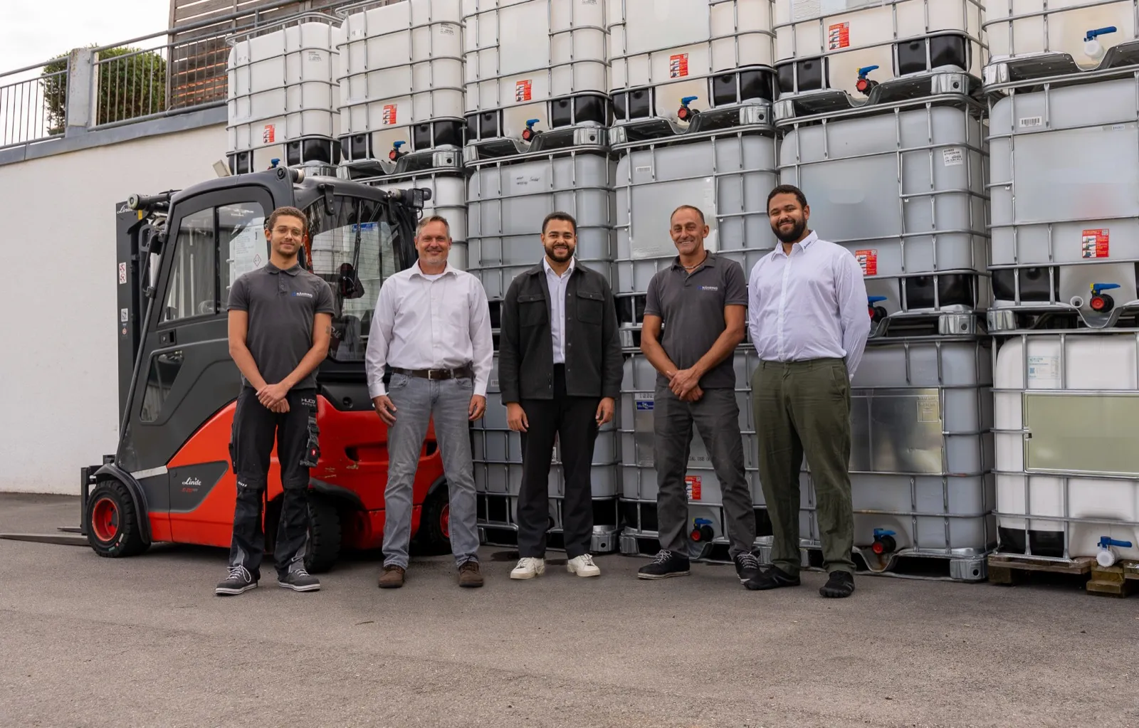 Das Team von Dr. Nähring vor gestapelten IBC-Containern